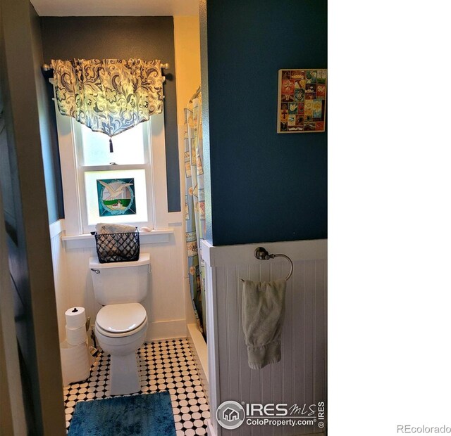 bathroom featuring toilet, a shower with shower curtain, and tile patterned flooring