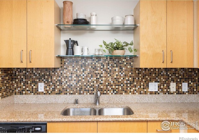 kitchen featuring sink, dishwashing machine, light stone countertops, and backsplash