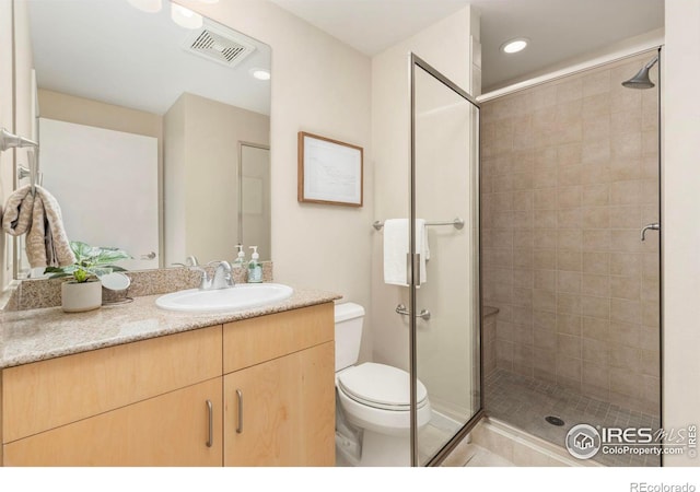 bathroom with a shower with door, vanity, and toilet