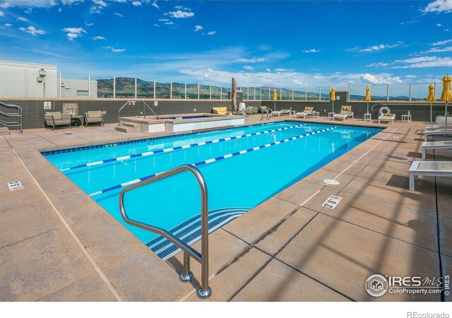 view of swimming pool featuring a hot tub and a patio area