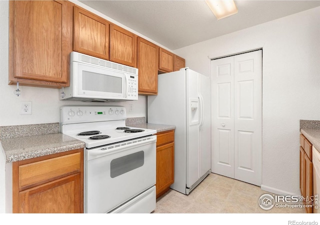 2990 W C St Unit 103, Greeley, CO 80631 - kitchen featuring white appliances, light countertops, brown cabinetry, and light tile patterned floors
