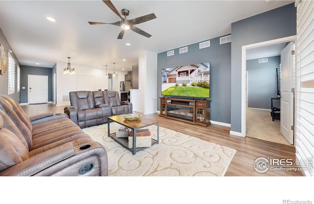 living room featuring light hardwood / wood-style flooring and ceiling fan with notable chandelier