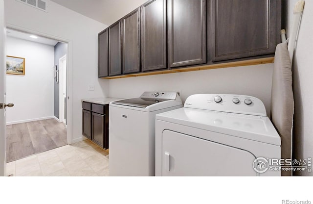 clothes washing area featuring washer and clothes dryer and cabinets