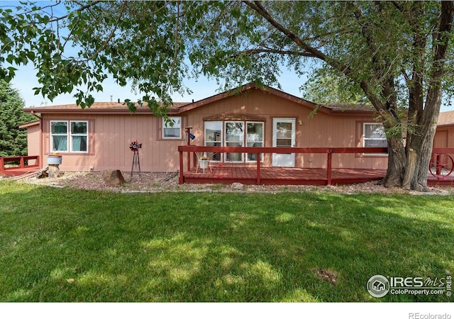 rear view of property featuring a lawn and a deck