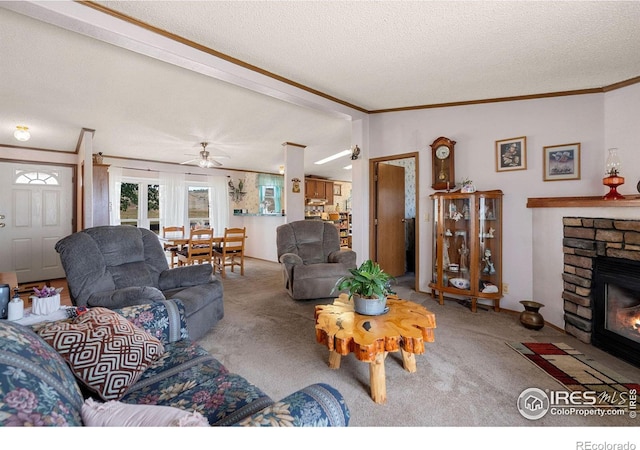 living room featuring carpet, ceiling fan, ornamental molding, a fireplace, and a textured ceiling