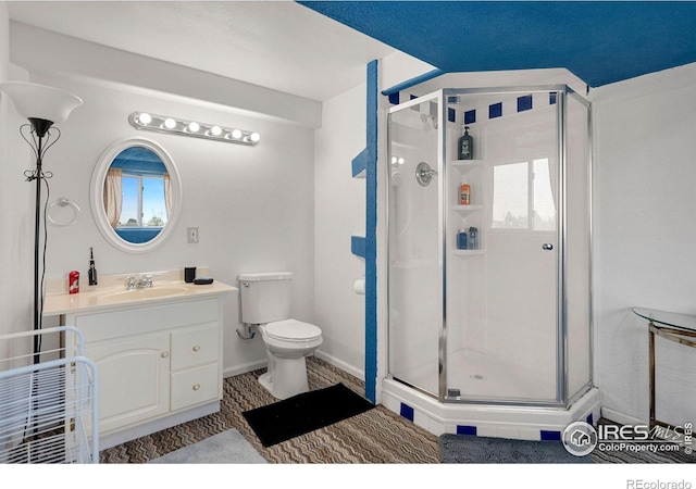 bathroom featuring vanity, a shower with shower door, and toilet