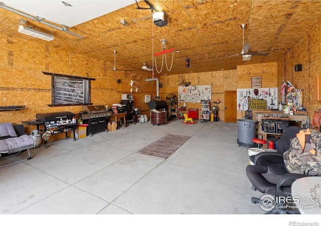 garage featuring a garage door opener, ceiling fan, and a workshop area