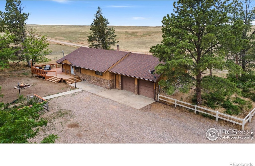 view of front facade featuring a deck, a garage, and a rural view