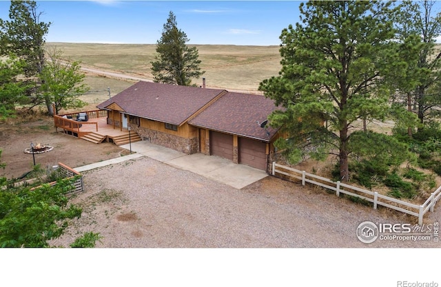 view of front facade featuring a deck, a garage, and a rural view