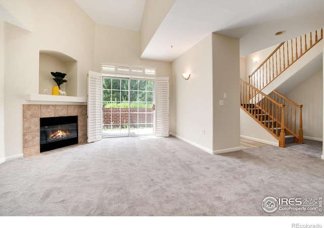 unfurnished living room featuring a fireplace, carpet flooring, and high vaulted ceiling