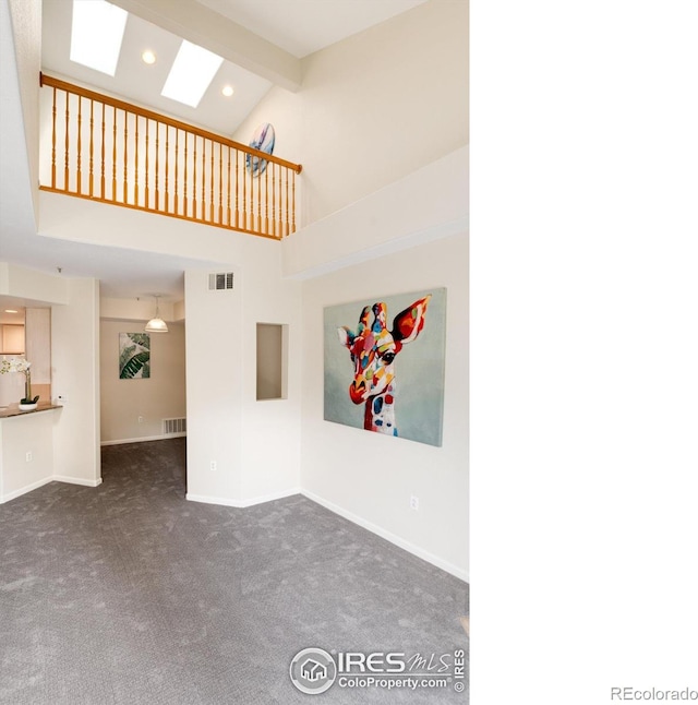 unfurnished living room with dark colored carpet, beam ceiling, a skylight, and high vaulted ceiling