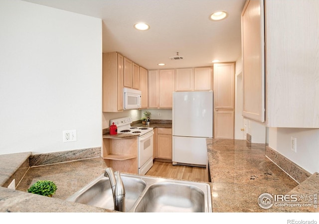 kitchen with light brown cabinets, white appliances, and sink