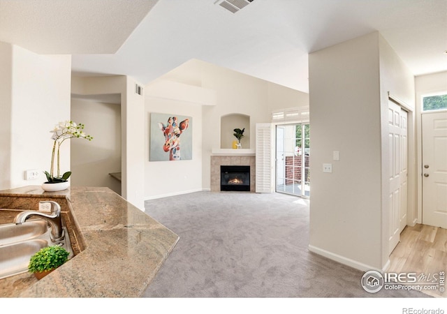 carpeted living room featuring sink and a tile fireplace