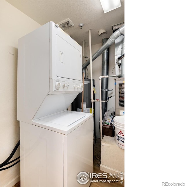 washroom featuring a textured ceiling and stacked washer and dryer