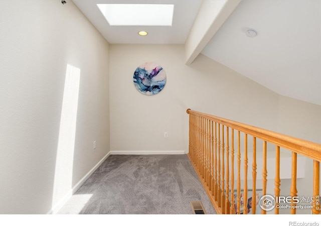 corridor with vaulted ceiling with skylight and carpet