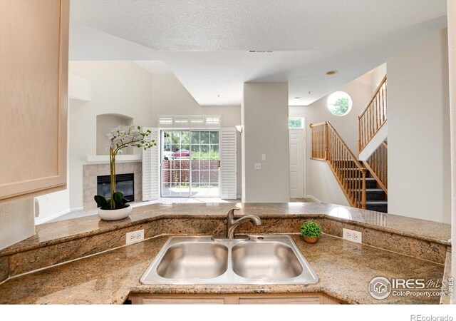 kitchen featuring a textured ceiling, sink, and a tiled fireplace