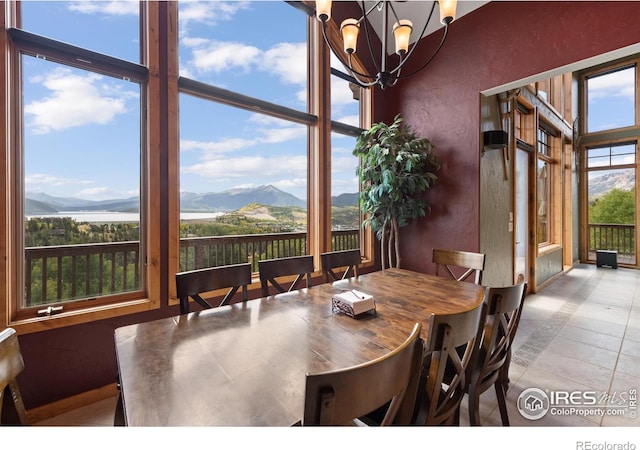 tiled dining room with floor to ceiling windows, a healthy amount of sunlight, a chandelier, and a mountain view