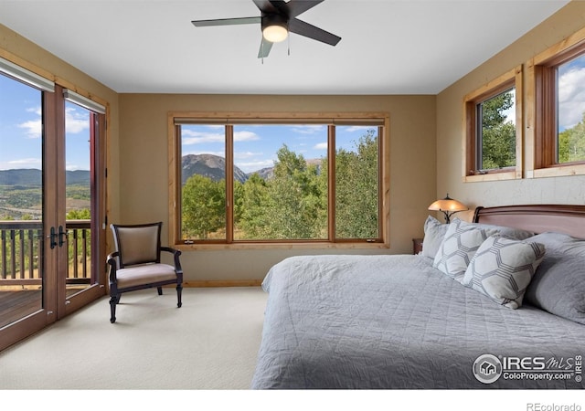 bedroom with access to outside, ceiling fan, a mountain view, and multiple windows