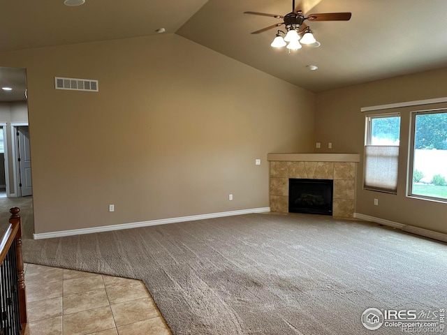 unfurnished living room with ceiling fan, vaulted ceiling, a fireplace, and light carpet