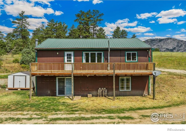 rear view of house featuring a storage shed, a mountain view, and a yard