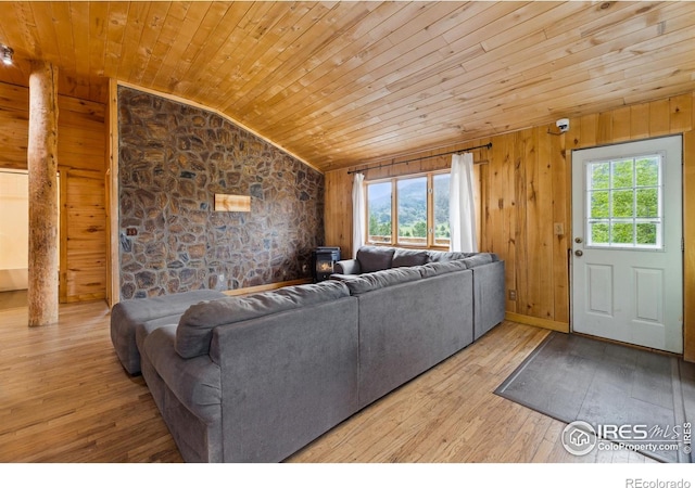 living room with lofted ceiling, wood walls, light hardwood / wood-style flooring, and wooden ceiling