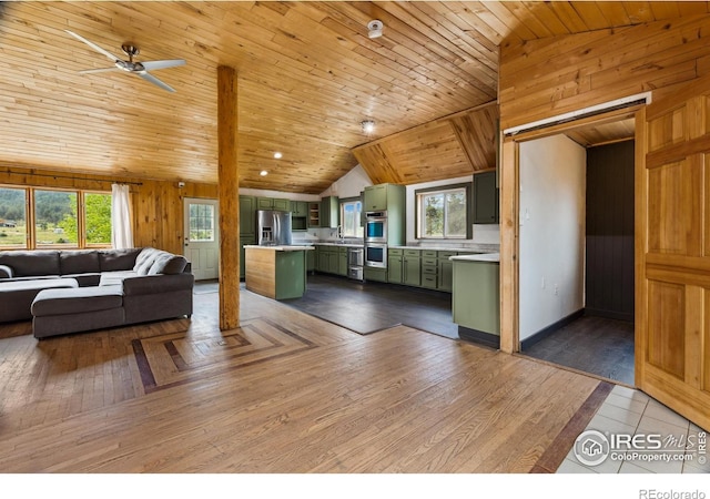 living room featuring ceiling fan, hardwood / wood-style floors, wood walls, lofted ceiling, and wood ceiling