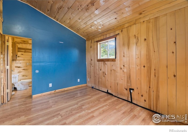 unfurnished room with wood walls and light hardwood / wood-style floors