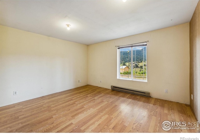 unfurnished room with a baseboard radiator and light wood-type flooring