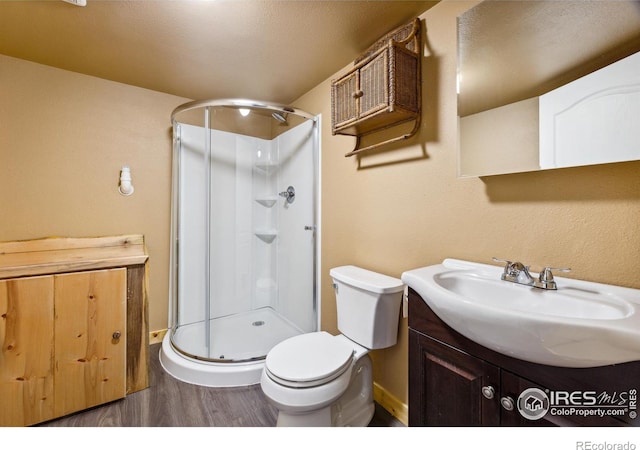 bathroom with vanity, toilet, a shower with door, and wood-type flooring