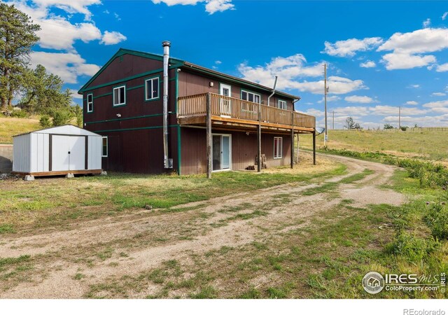 back of property with a storage unit and a wooden deck