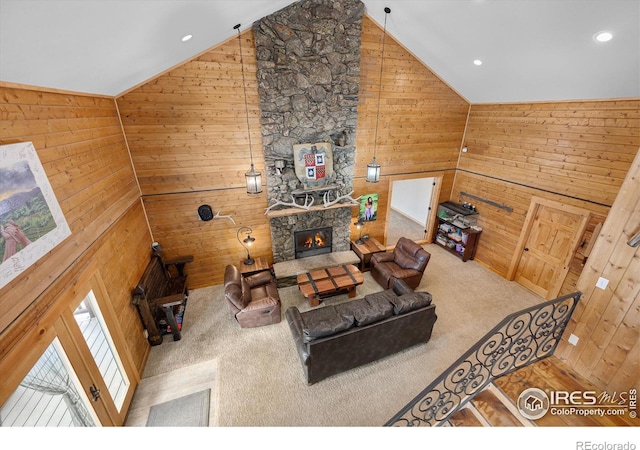 living room with a fireplace, high vaulted ceiling, wooden walls, and carpet floors