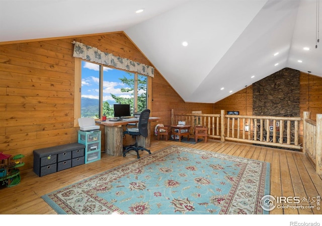 office space with vaulted ceiling, light hardwood / wood-style floors, and wood walls