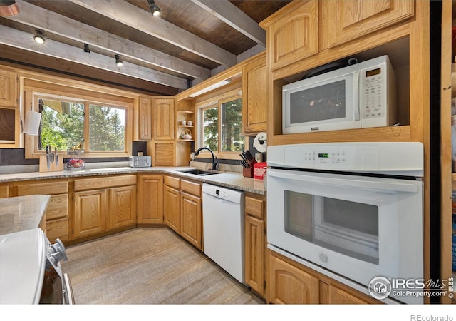 kitchen with sink, beamed ceiling, white appliances, light stone countertops, and light hardwood / wood-style floors