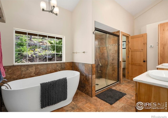 full bathroom with plus walk in shower, vaulted ceiling, a chandelier, vanity, and toilet