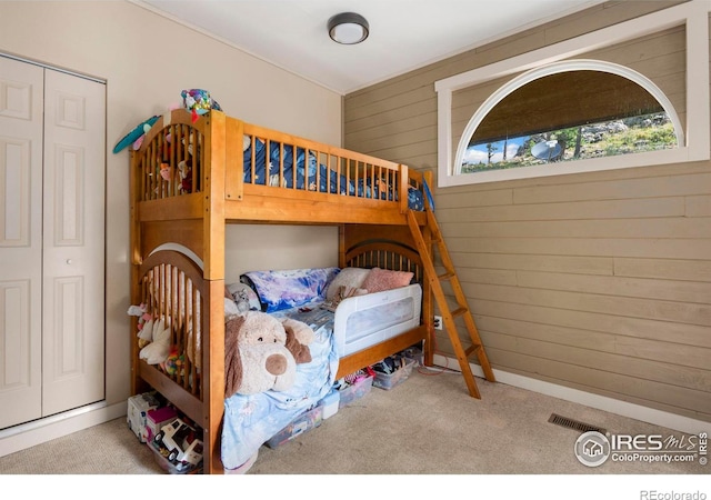 bedroom featuring wooden walls, light colored carpet, and a closet