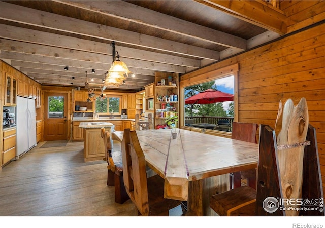 dining area featuring wooden ceiling, beam ceiling, light wood-type flooring, and wood walls