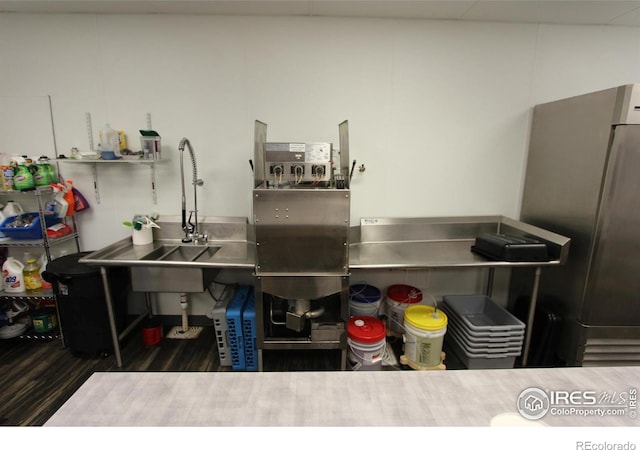 kitchen featuring stainless steel counters, a sink, and freestanding refrigerator