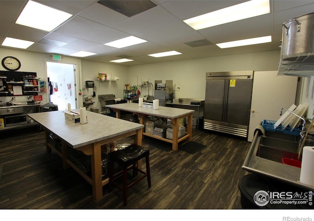 kitchen with high end refrigerator, dark wood finished floors, and a drop ceiling