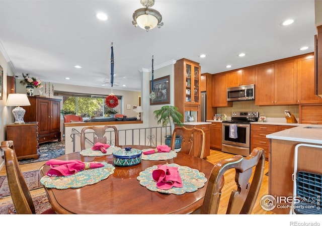 dining space with light hardwood / wood-style flooring and crown molding