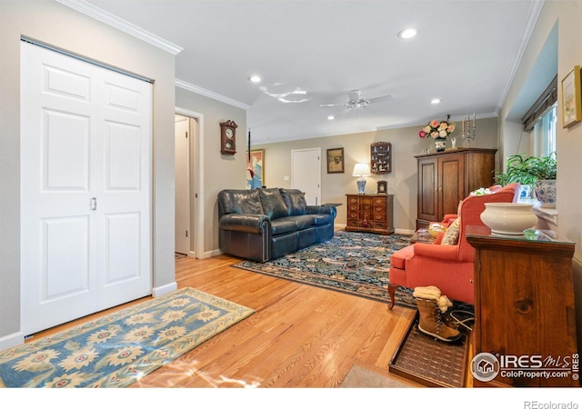 living room with ceiling fan, crown molding, and light hardwood / wood-style floors