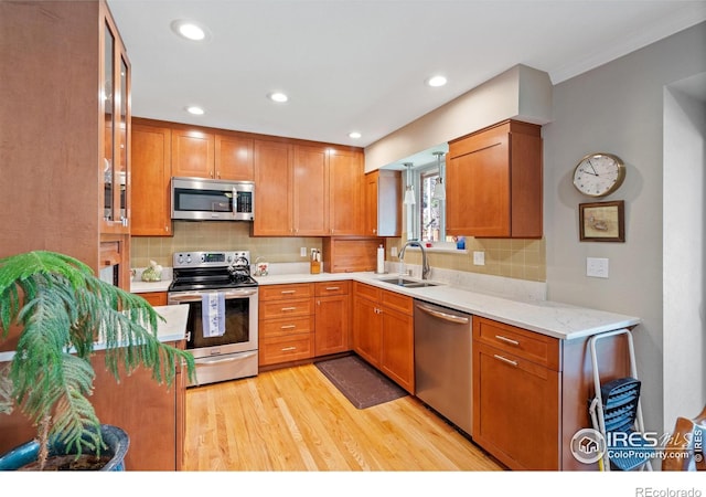 kitchen featuring stainless steel appliances, light hardwood / wood-style flooring, tasteful backsplash, and sink