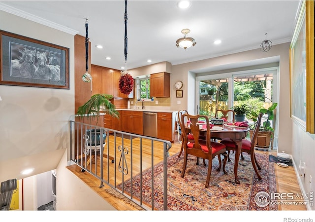 dining room featuring sink, crown molding, and light hardwood / wood-style floors