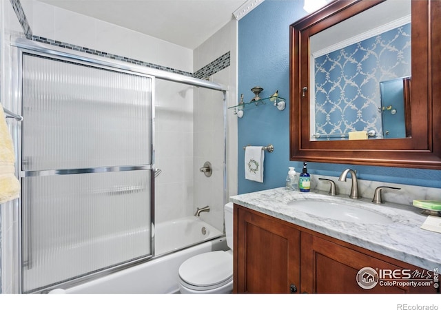 full bathroom featuring toilet, bath / shower combo with glass door, and vanity