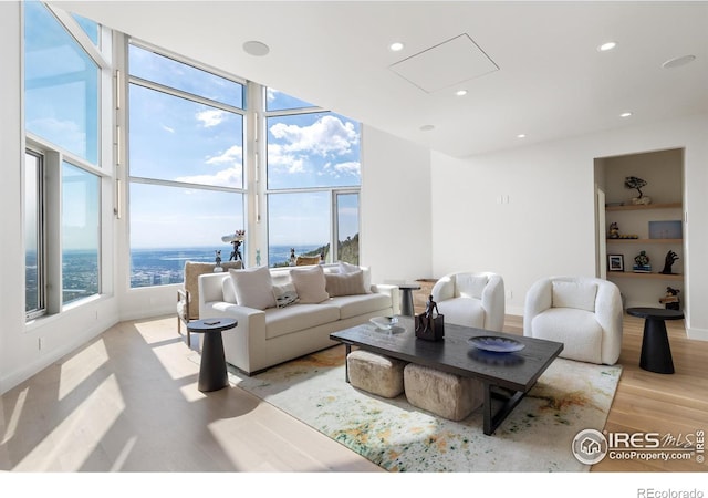 living room featuring light hardwood / wood-style flooring, a water view, and expansive windows