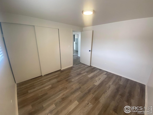 unfurnished bedroom with dark hardwood / wood-style floors and a closet