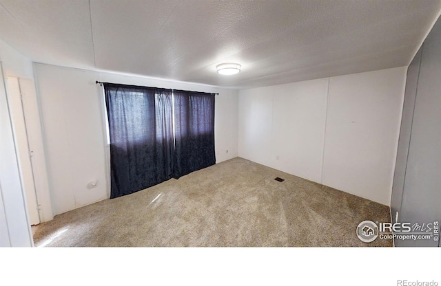 spare room featuring carpet and a textured ceiling