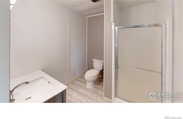 bathroom with toilet, a shower with door, hardwood / wood-style floors, and vanity