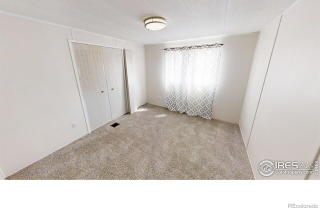 unfurnished bedroom featuring light carpet, a closet, and a textured ceiling