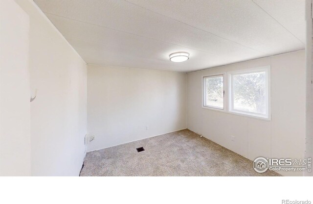 carpeted empty room featuring a textured ceiling