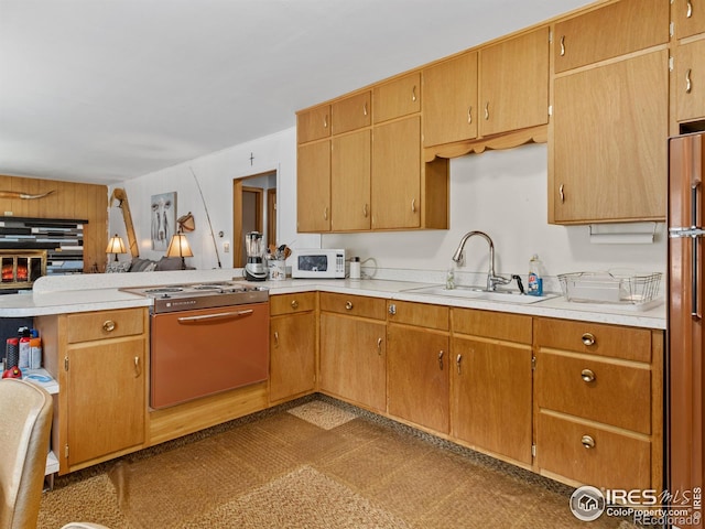 kitchen featuring stainless steel refrigerator, kitchen peninsula, and sink